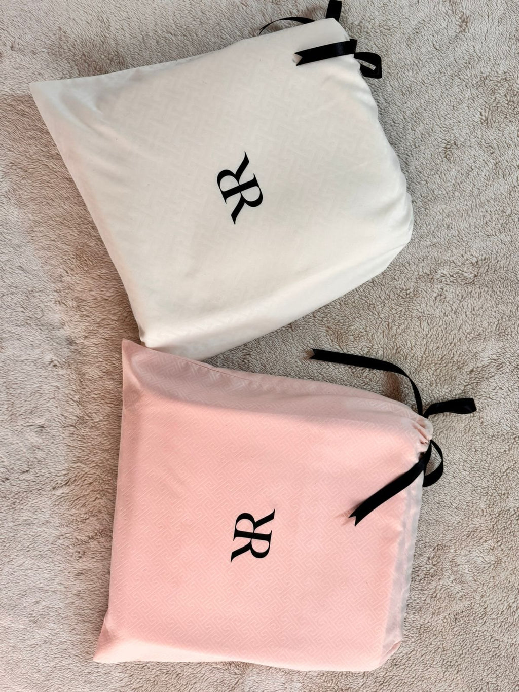 Juego de sábanas Rosas Home en bolsas de jacquard marfil y rosa con monograma RR y cinta de satín negro