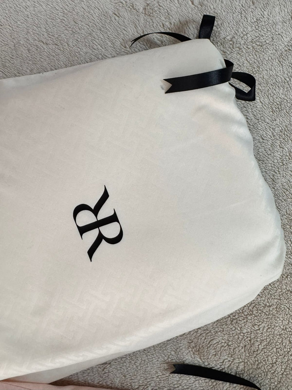 Bolsa de jacquard marfil con monograma RR y cinta de satín negro, empaque del juego de sábanas Rosas Home